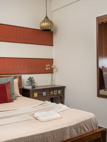 Bedroom corner with terracotta tiled headboard, brass pendant light, and wooden bedside table