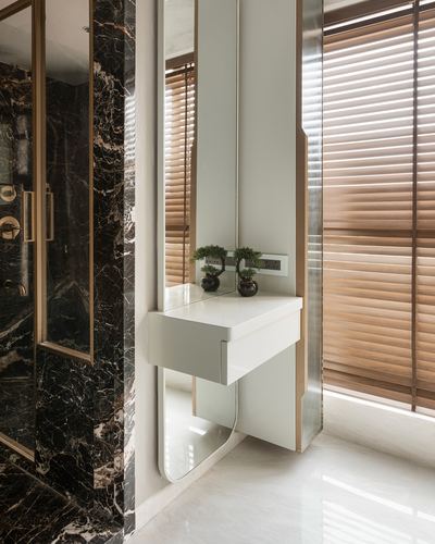 Floating white vanity with mirror beside dark marble wall and wood-blind window