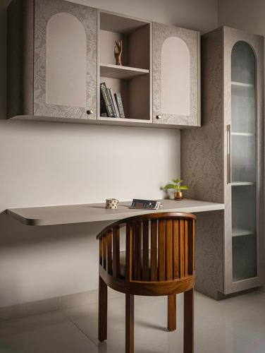 Wall-mounted study desk with arched patterned cabinets above and a wooden barrel chair below