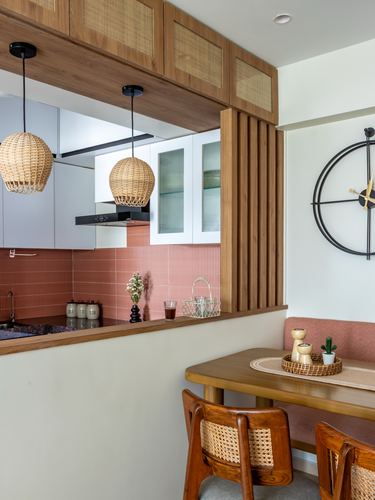 Kitchen pass-through with rattan pendants and terracotta tile beside a cane dining nook