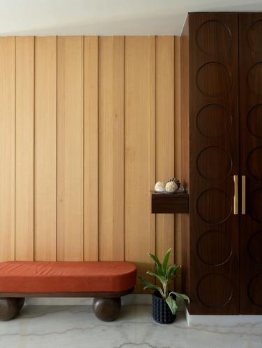 Fluted wood wall with terracotta bench and dark carved wardrobe in entry foyer