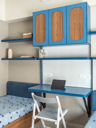 Kid's room with blue wall-mounted desk, floating shelves, and arched wood cabinet above bed