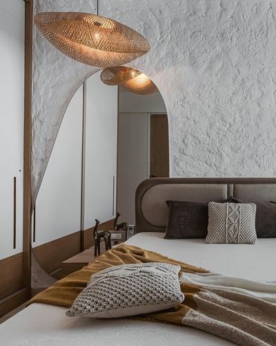 Bedroom with arched mirror, woven pendant lights, and mustard throw on upholstered bed