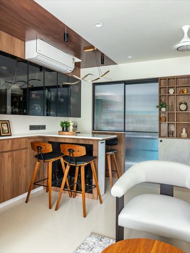Wood-toned kitchen with island, bar stools, black glass cabinets and fluted glass sliding door