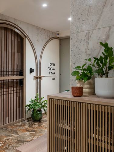 Entryway with arched doorway, marble wall, wooden slatted console and potted plants