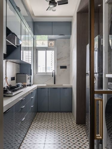 Narrow galley kitchen with grey glossy cabinets, marble-look backsplash, and patterned floor tiles
