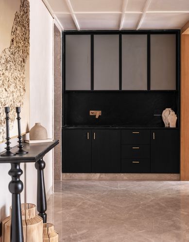 Black cabinetry with frosted glass panels in a marble-floored foyer with a black console table