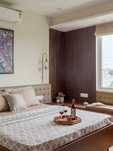 Bedroom with tufted headboard, fluted wood wall, and window seat bathed in daylight