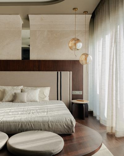 Neutral bedroom with marble headboard wall, wood paneling, and amber glass pendant lights beside bed