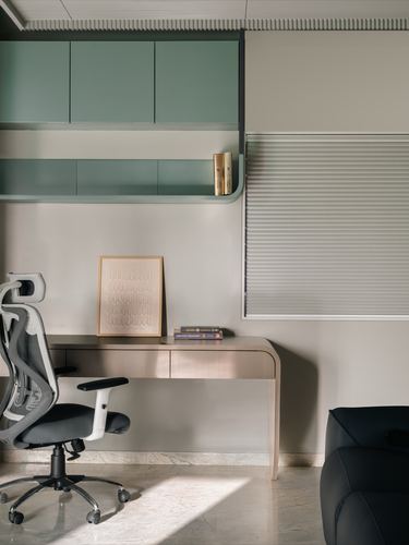 Minimalist home study with sage cabinetry, wood desk, mesh chair and roller blind window