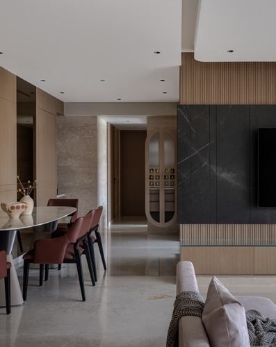 Open living-dining space with stone floors, fluted wood wall, dark stone tv panel, and leather dining chairs