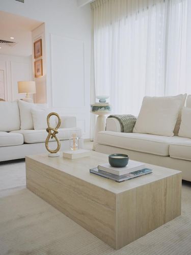 Neutral living room with cream sofas, stone coffee table, and sheer curtained window