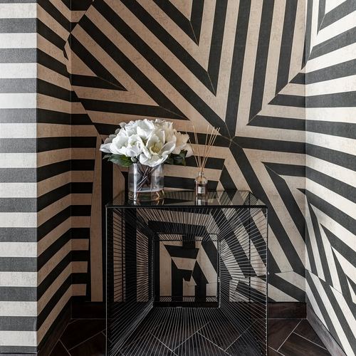 Black and white striped geometric wallpaper corner with mirrored metal console table holding white flowers