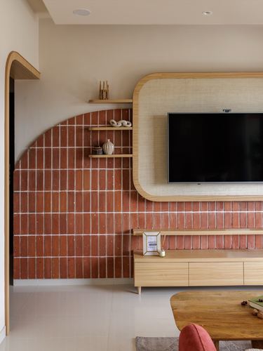 Living room with rust brick wall, arched doorway, and rounded wood-framed TV niche above a wooden console