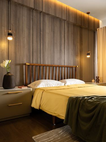 Bedroom with ribbed wood panel wall, spindle headboard, mustard bedding and pendant lights