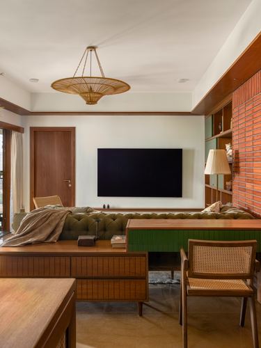 Living room with tufted olive sofa, wooden console, cane chair and brick accent wall