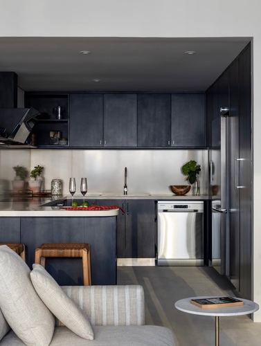 Dark indigo L-shaped kitchen with pale stone island and stainless steel appliances
