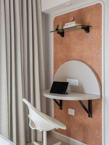 Small semicircular wall-mounted desk with tablet, set against a textured terracotta wall panel with glass shelf above.