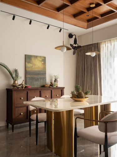Dining room with marble-top brass table, cane and velvet chairs, and coffered wood ceiling