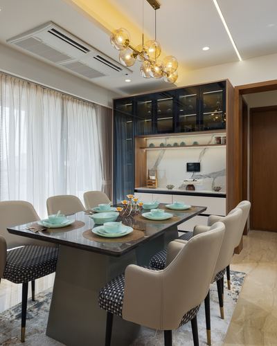 Dining room with marble table, cane-back chairs, glass cabinet and cluster pendant light