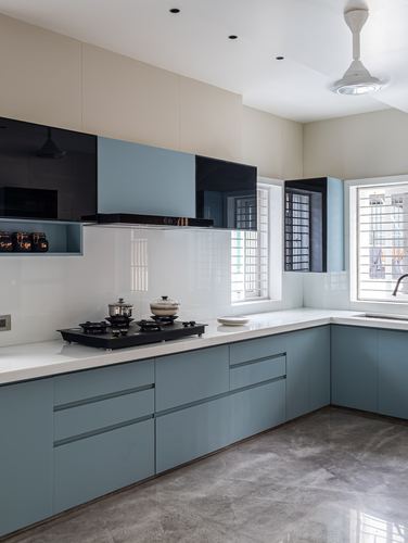 Modern L-shaped kitchen with blue glossy cabinets, white countertop, and grey stone flooring