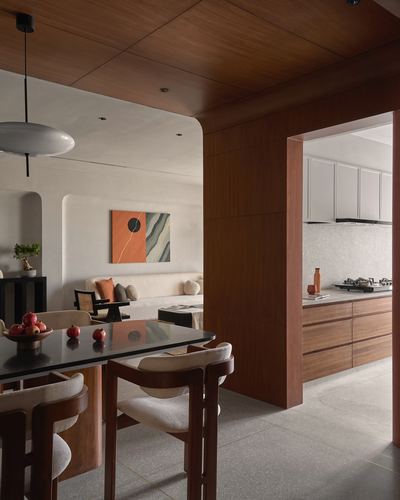 Dining area with curved wood archway opening to kitchen, terrazzo floor and pendant light