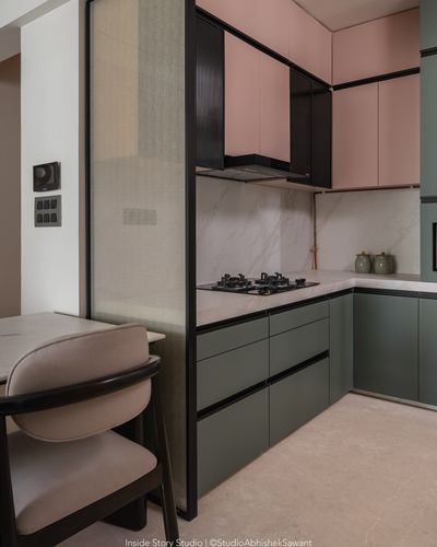 Pink and green kitchen cabinetry with marble-look backsplash beside a dining nook.