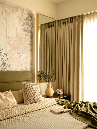 Bedroom corner with arched mirror, olive headboard, pleated curtains, and tree wallpaper niche