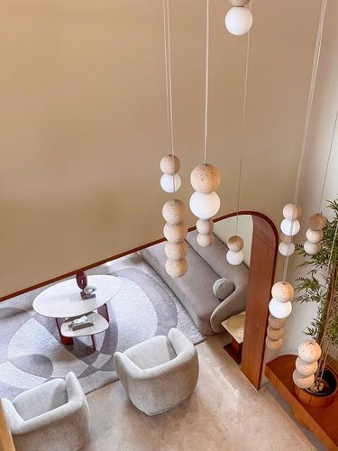 Overhead view of a minimalist living nook with sphere pendant lights, round table, and curved sofa