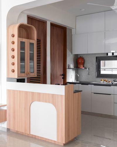 Curved wooden island and arched cabinet frame an open kitchen with white glossy cabinetry