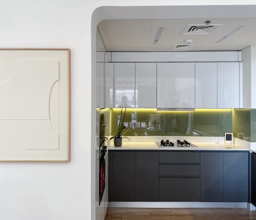 Modern white and charcoal galley kitchen seen through an arched opening, framed art beside it