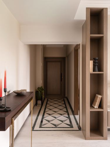 Entry corridor with wood shelving, dark console, and geometric marble floor inlay leading to a door
