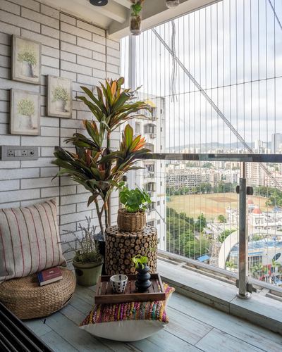 Boho balcony seating nook with brick wall, plants, and city skyline view
