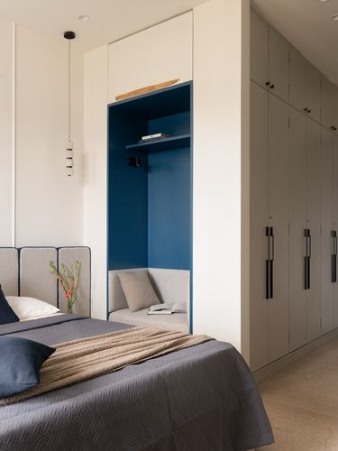 Bedroom with built-in blue reading nook, tall wardrobes, and grey bed with pendant lights