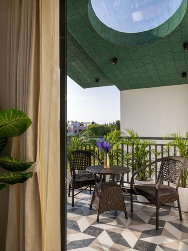 Balcony with rattan chairs and geometric floor tile beneath a green-tiled ceiling with an oval skylight cutout