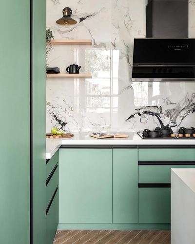 Sage green modular kitchen with white marble-look backsplash and black chimney hood