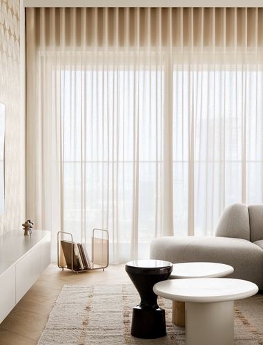 Neutral living room with sheer curtains, rounded coffee tables, and a curved sofa