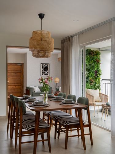 Dining room with wood table, striped chairs, rattan pendant light and balcony vertical garden beyond