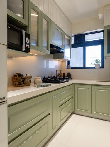 L-shaped kitchen with sage green cabinets, white countertop, gas hob and window over sink