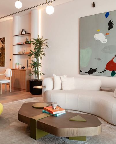 Curved white sofa and organic wood coffee table in a neutral toned living room with abstract art