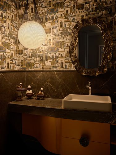 Powder room with illustrated wallpaper, globe pendant, sculpted brass mirror and marble vanity