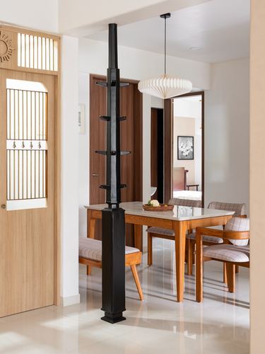 Dining area seen through foyer with black vertical shelf column and paper pendant light