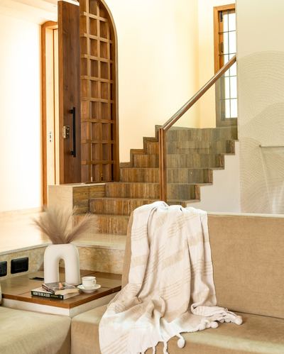 Arched wooden lattice door beside a stone staircase with a draped throw on a beige sofa