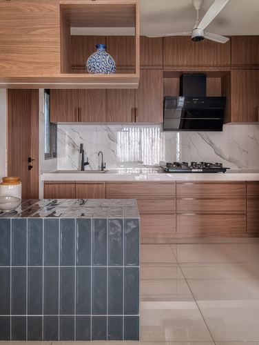 Kitchen with teak-toned cabinetry, marble-look backsplash, and a blue tiled island in foreground