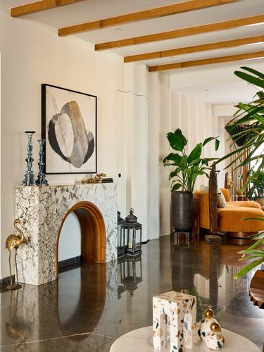 Living room with arched marble console, exposed wood ceiling beams, and orange sofa beyond.