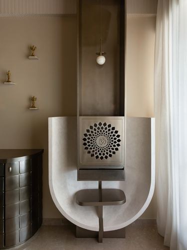 Sculpted stone arch pooja niche with carved om medallion panel and hanging pendant light