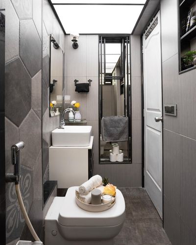 Narrow modern bathroom with grey hexagonal tile, white sink, and styled toilet tray