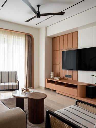 Living room with wood-panelled TV wall, curved archway, nesting round tables and striped armchair