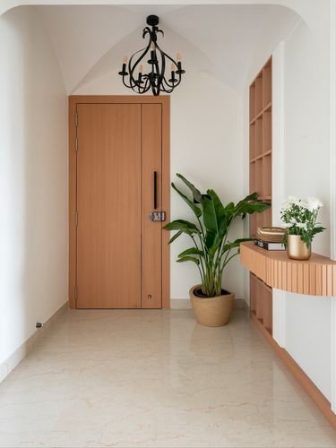 Foyer with wooden door, black chandelier, plant, and wood shelving unit