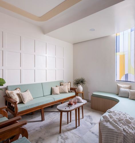 Sage green sofa and curved bench in a paneled living room with marble floor and stained glass window